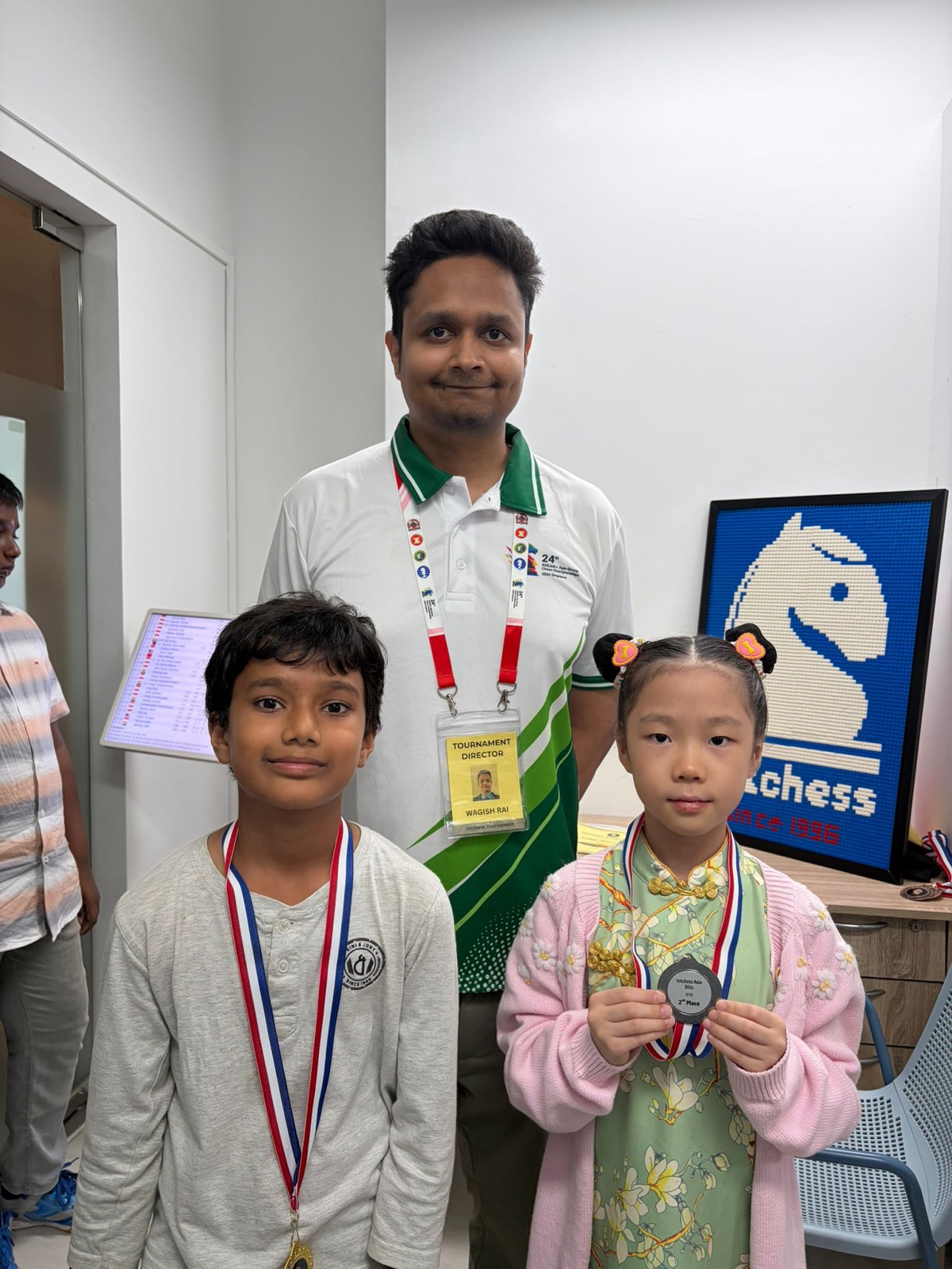 Two IntChess students with their coach after receiving tournament medals